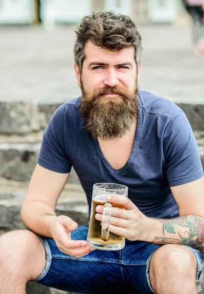 Café terrasse d'été. Des bières claires ou des stouts sombres les boivent toutes. Homme avec barbe et moustache tenir verre de bière à l'extérieur. Le type se repose avec de la bière fraîche. Hipster détendu boire de la bière en plein air — Photo