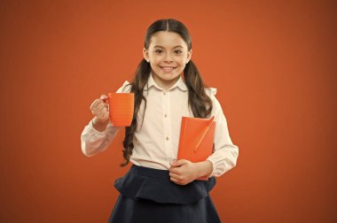 Tüm mutluluk okul kahvaltısı bağlıdır. Küçük kız turuncu arka plan onu okul molası zevk. Sevimli okul çocuk fincan ve not defteri ile gülümseyen. Mutlu kız öğrenci okulda sıcak içki olan