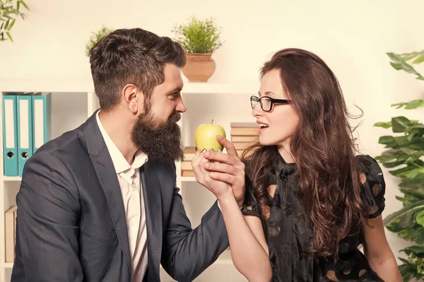 苹果富含维生素.老板和性感秘书在办公室里拿着维生素水果.有胡子的男人和性感女人工作时都有健康的维生素小吃。维生素食品实际上是有效的 — 图库照片