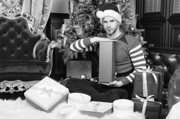 E 'il miglior Natale di sempre. Uomo in cappello di Babbo Natale tenere regali di Natale. Consegna regali di Natale. Uomo felice con scatole regalo di Natale. Guy festeggia il Natale a casa — Foto Stock