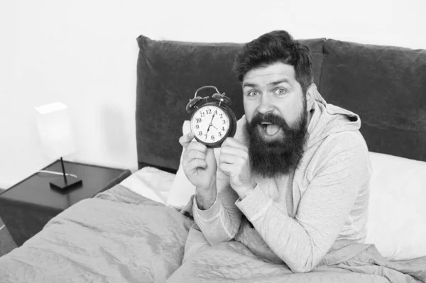 Man bearded hipster sleepy face waking up. Daily schedule for healthy lifestyle. Again unhappy in morning. Alarm clock ringing. Problem early morning awakening. Get up early. Tips for waking up early