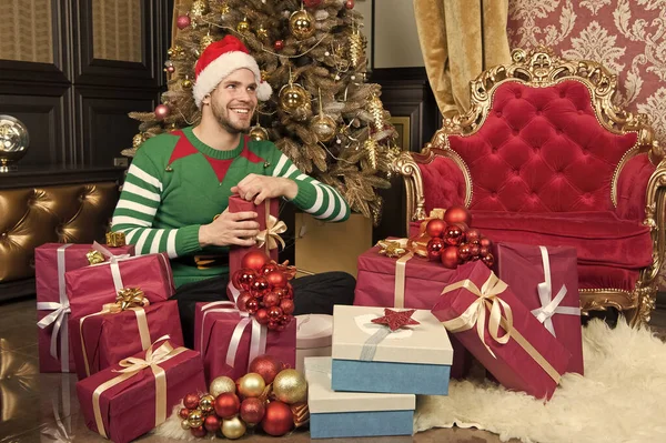 Dat krijg je alleen met Kerstmis. Levering Kerstcadeaus. Guy is het vieren van Kerstmis thuis. Man in KERSTMUTS houden Kerstcadeaus. Gelukkig man met kerst geschenkdozen. Het seizoen als jolly — Stockfoto