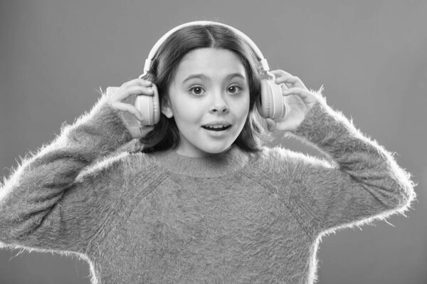 Radio app for your mobile device. Music is her soul. Girl cute little child wear headphones listen music. Kid listen music orange background. Recommended music based on your initial interest