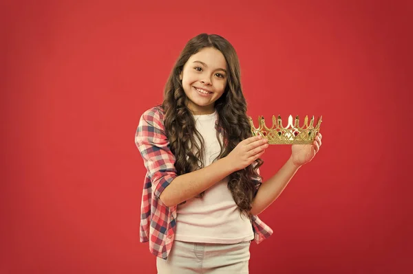 Una recompensa muy rica. Niña sosteniendo la recompensa de la corona sobre fondo rojo. Éxito pequeño ganador con preciosa recompensa por el éxito. Ganar un valioso premio y recompensa — Foto de Stock