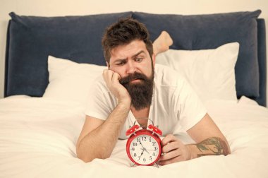 Yatakta depresif bir adam. zaman yönetimi. çalar saat ile yorgun sakallı adam hipster. yatak odasında acımasız uykulu adam. yatakta pijama sakallı olgun erkek. uykuda ve uyanık. enerji ve yorgunluk