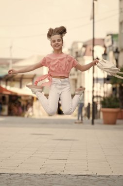 Daha yüksek ve daha aktif oluyor. Aktif küçük kız şehir arka planda hareket ediyor. Mutlu küçük çocuk zevk için aktif atlama. Aktif ve enerjik çocuk yaz aylarında eğleniyor