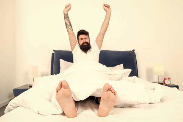 Giornata spensierata a casa. brutale uomo assonnato in camera da letto. addormentato e sveglio. Buongiorno. Ciao. maschio con barba in pigiama sul letto. energia e stanchezza. Che mattinata fantastica. barbuto uomo hipster sonno al mattino — Foto Stock