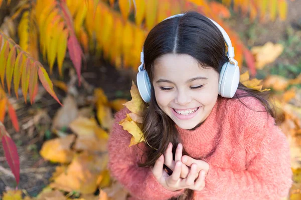 Poczuć radość. Kid girl relaks w pobliżu jesiennego drzewa ze słuchawkami. Muzyka na jesienny nastrój przytulny. Koncepcja jesiennej playlisty. Ciesz się muzyką na świeżym powietrzu jesień ciepły dzień. Słuchanie piosenki. Plik audio. Podcast edukacyjny — Zdjęcie stockowe
