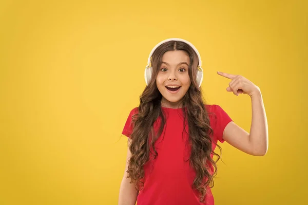 De la musique à vos oreilles. Adorable enfant écouter de la musique dans les écouteurs sur fond jaune. Petite fille appréciant sa musique préférée. Petit enfant mignon écoutant de la musique dans un casque, espace de copie — Photo