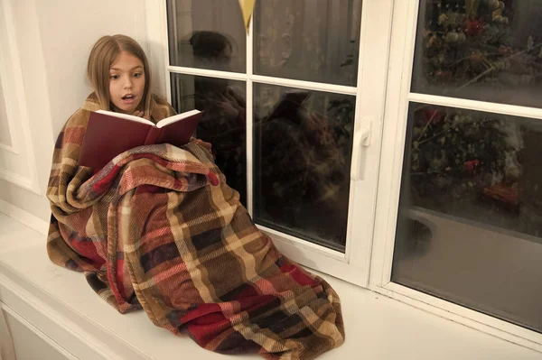 为了非常快乐的假期。儿童画册。小女孩喜欢读圣诞故事。小孩在圣诞前夜看书。格子里的小读者坐在窗台上。神奇的圣诞精神 — 图库照片