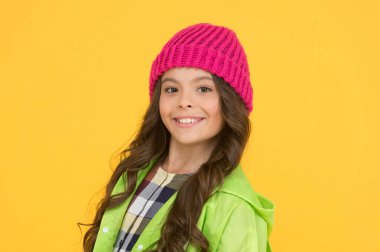 Başını sıcak tut. Mutlu çocuk, trend sokak görünümlü bir bere takıyor. Modayla gülümseyen küçük kız. Moda mankeni modası. Çocuk modası ve aksesuar. Samimi sonbahar görünüşü