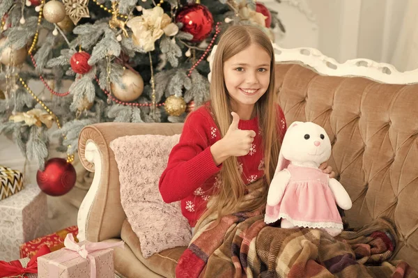 나는 그것을 대단히 좋아하지. 어린 소녀는 크리스마스 나무에서 귀여운 토끼 최대 엄지. 작은 소녀는 토끼 장난감을 잡아. 부드러운 장난감 작은 아이 놀이. 작은 아이가 현재 함께 웃 고 행복. 최고의 크리스마스 장난감 — 스톡 사진