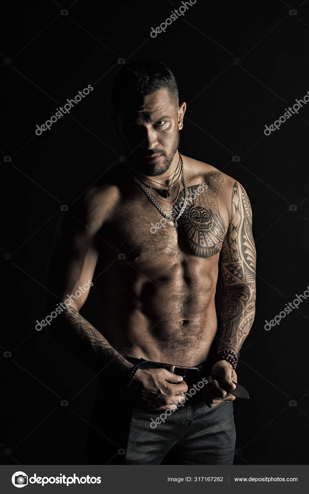 Bearded man shirtless with fit torso. Man with tattoo design on skin.  Fashion model buckle leather