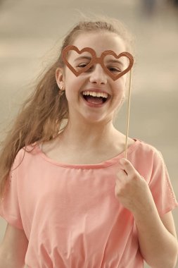 Sevgililer günün kutlu olsun. Mutlu gülümseme ve kalp şeklinde gözlük ile komik bir görünüm ile küçük çocuk. Mutlu küçük kız sopa üzerinde photobooth sahne ile gülümseyen. Mutlu uluslararası çocuk gününü kutluyoruz