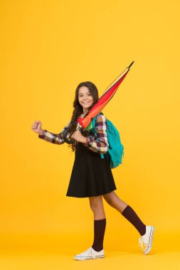 Sadece yağmur yağdığında mutlu olurum. Mutlu kız okula gidiyor. Küçük kız yağmurlu hava için sopa şemsiyesi taşıyor. Küçük kız okul elbisesi ve sırt çantası giyiyor. Kız çocuk eğitimi. Her hava şartında okula dönüyorum.