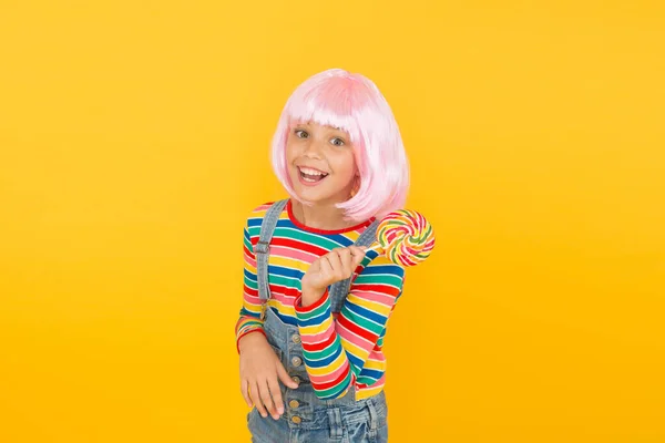 Her favorite rainbow swirl dessert on stick. Small child enjoy hard candy dessert yellow background. Little girl prefer sweet dessert to healthy food. Treat or dessert — Stock Photo, Image