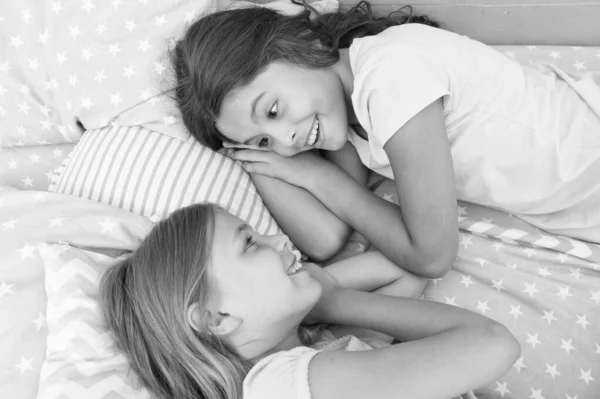 Nincs barátja, mint egy húga. Boldog kis nővérek beszél közben nap idő. Kis nővérek pihennek az ágyban együtt. Az imádnivaló nővér vagy barátai élvezik a pihenés órát — Stock Fotó