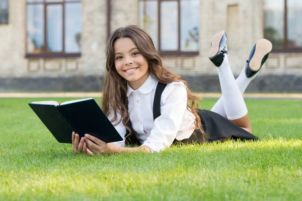 Ta kniha je geniální. Geniální knihomol relaxovat čtení na zelené trávě. Šťastný malý génius čte knihu venku. Malé zázračné stvoření. Zázračné dítě. Zpět na geniální školu — Stock fotografie