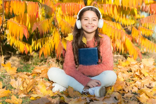 Uczennica się uczy. Ucz się codziennie. Dziewczyna czyta książki jesienią. Koncepcja samoedukacji. Dziecko lubi czytać. Informacje wizualne i dźwiękowe. Małe dziecko lubi uczyć się na podwórku. Nauka dla dzieci z książką — Zdjęcie stockowe