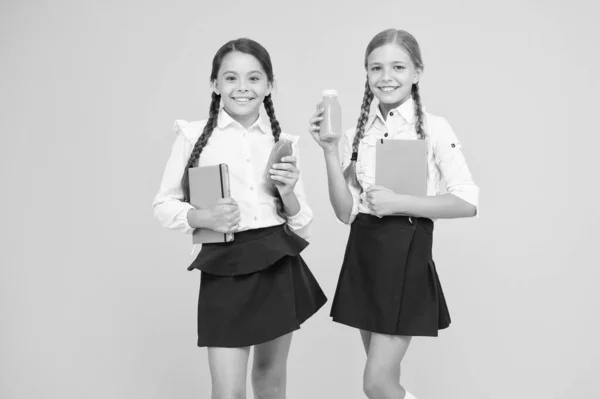 Delicioso batido. Nutrición saludable. Colegialas sosteniendo la botella de jugo sobre fondo amarillo. Apagando la sed durante la escuela. Sed y deshidratación. Batido saludable de frutas de aperitivo. Desintoxicación del batido — Foto de Stock