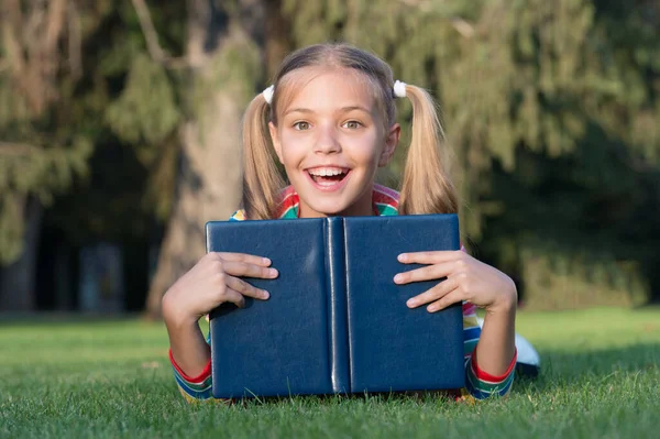 Świetne miejsce do czytania. Szczęśliwe małe dziecko czyta książki biblioteczne na zewnątrz. Urocza dziewczynka uczy się czytać w podstawówce. Będę czytał wszędzie. — Zdjęcie stockowe