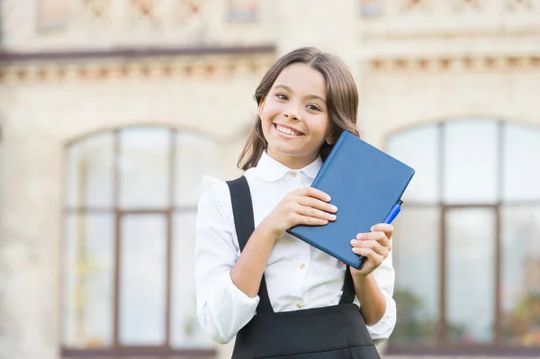 Willkommen zurück in der Schule. glückliche kleine Mädchen gehen aus der Schulbibliothek. Nettes Grundschulkind lächelt mit Buch in der Hand. Vorbereitung auf die Schule. 1. September Wissenstag. Frühe Bildung — Stockfoto