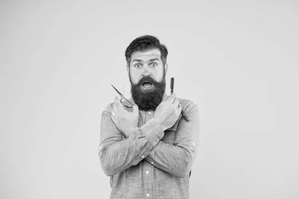 Wauw. Kapper met een verbaasd baardgezicht. Baard en ongeschoren hipster met kappersgereedschap. De man met de baard heeft een schaar en een vlijmgele achtergrond. Trendy kapsel voor bebaarde man — Stockfoto