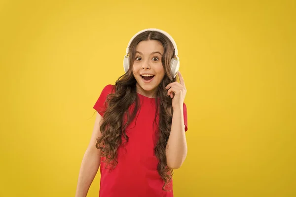 Tekniken är underbart när det fungerar. Lycklig liten flicka lyssnar på musik i hörlurar på gul bakgrund. Litet barn som njuter av stereoljud teknik. Ny teknik. Teknikkoncept — Stockfoto