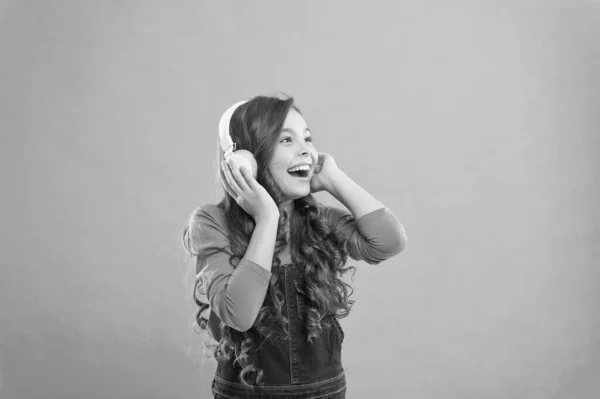 A música soa melhor com os meus auscultadores. Menina usando fones de ouvido no fundo azul. Criança bonito ouvir música em fones de ouvido estéreo. Criança pequena adorável usando fones de ouvido modernos — Fotografia de Stock