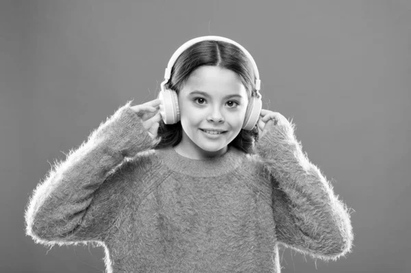 为您的移动设备提供最好的免费音乐应用。享受声音。女孩可爱的小孩戴耳机听音乐。孩子听音乐橙色背景。基于初始兴趣的推荐音乐 — 图库照片