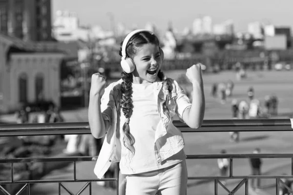 I aint nothing but a winner. Happy small child shouting and making winner gesture on summer day. Happy girl winner headphones for listening to music. Excited little winner celebrating victory
