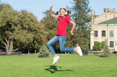 Sürücü dansçılığı mükemmelliği. Küçük dansçı yeşil çimlerde zıpladı. Tatlı kız dansçı enerjik dans ediyor. Kulaklıkla müzik çalan sevimli küçük dansçı.