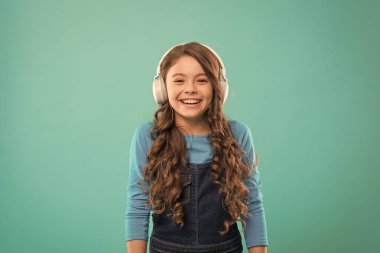 Anı oyna. Stereo kulaklıkla müzik dinleyen sevimli çocuk. Mavi arka planda sevimli kulaklık kullanıcısı. Ayarlanabilir beyaz kulaklık takan küçük çocuk. Kablosuz kulaklık kullanan küçük kız