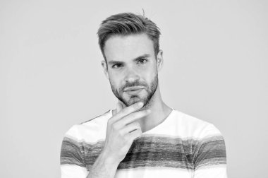 Orta derecede sakallı. Sarı zeminli sakallı adam. Traşsız adam sakallı çenesine dokunuyor. Sakallı yüzünde bıyık lı ve sakallı yakışıklı beyaz model