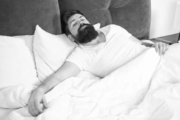 Sleep disorders concept. Man bearded hipster having problems with sleep. Guy lying in bed try to relax and fall asleep. Relaxation techniques. Violations of sleep and wakefulness. What a long night