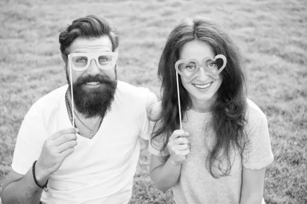 Love story. Happy together. Couple in love cheerful youth booth props. Couple relaxing green lawn. Man bearded hipster and pretty woman in love. Summer vacation. Emotional couple radiating happiness