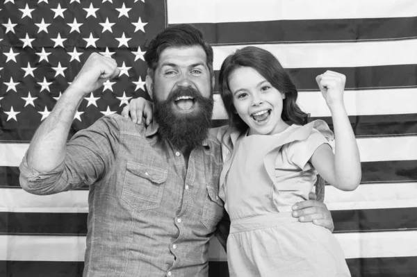 Proud to be americans. Happy american family celebrating Independence day. Bearded man and little child with winner gestures on american flag background. Living the American dream