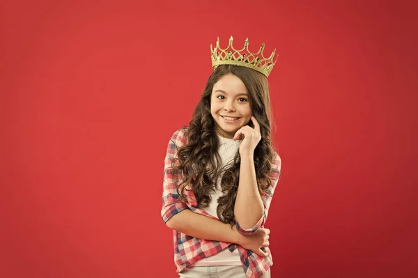 Fuente de orgullo. Niña orgullosa llevando la joya de la corona con orgullo sobre fondo rojo. Adorable niño pequeño con el pelo rizado largo sintiendo gran orgullo. Concepto de orgullo — Foto de Stock