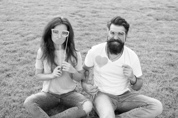 Couple in love cheerful youth booth props. Emotional people. Couple dating. Carefree couple having fun green lawn. Man bearded hipster and pretty woman cheerful faces. Youth day. Summer entertainment