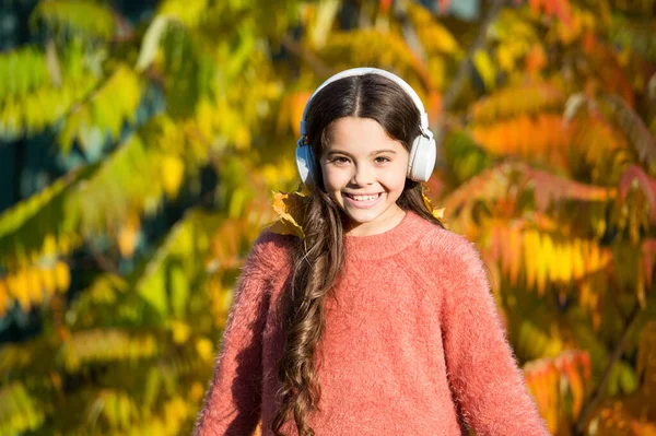 Muzyka na jesienny nastrój. Kid girl relaks w pobliżu jesiennego drzewa ze słuchawkami. Słuchanie piosenki. Miłego jesiennego dnia muzyki. Jesienne spacery z ładnymi piosenkami. Książki edukacyjne i do pobrania audio dla dzieci — Zdjęcie stockowe