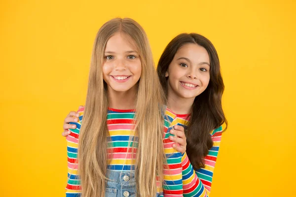 A gyerekek jelentik a jövőt. Boldog gyerekek hosszú haj sárga háttér. Kisgyerekek alkalmi stílusban. A kisgyerekek aranyos mosollyal. Nemzetközi gyermeknap — Stock Fotó