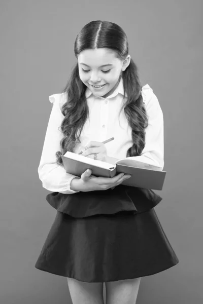 Rédigez un essai ou des notes. Inspiration pour l'étude. Je retourne à l'école. Journée du savoir. Les écolières aiment étudier. L'uniforme de l'école pour enfants tient le cahier. Leçon scolaire. Un enfant qui fait ses devoirs. Votre carrière commence ici — Photo