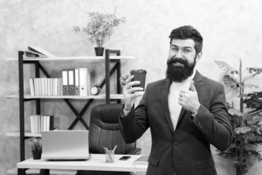 Uyarıcı almış olmalı. Adam sakallı yönetici iş adamı elinde bir fincan kahve tutuyor. Rahatlamış neşeli üst düzey yönetici kahve içiyor. Patron enerji içeceğini seviyor. İşçi güne kahveyle başlar