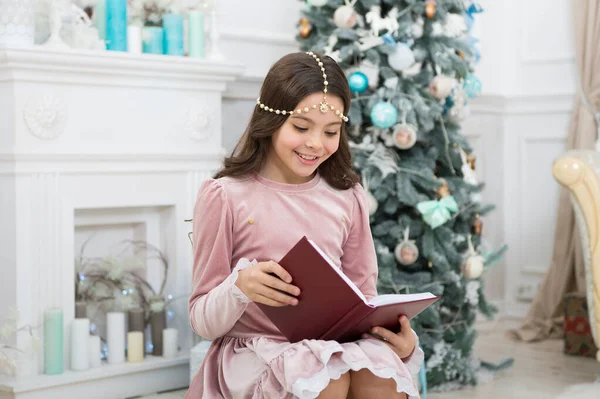 Christmas spirit. Little reader enjoy reading at home. Best Christmas book. Books shop commercial. Little smiling child read book. New year eve. Little girl reading Christmas story. Magic atmosphere