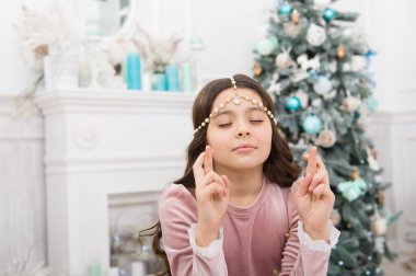 Umut kavramı. Rüya gibi bebek noel dileği. Dilek tutuyorum. Noel Baba 'yı bekliyorum. İç dekore edilmiş Noel ağacının yanında dilek tutan sevimli bir kız. Umutlu çocuk. Yeni yıl arifesi. Hayaller gerçek olur.
