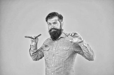 Eski kafalılıktan hippi şıklığına. Hippi, tıraş aletlerini sarı arka planda tut. Profesyonel berber hippi tarzında uzun sakal ve bıyık takar. Berber dükkanı. En iyi hippi berber, klasik.