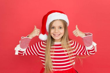 Noel partisi. Neşeli kız Noel arifesinde eğleniyor. En iyi dileklerimle. Neşeli çocuk. Çocuk Noel Baba kostümü mucizeye inanır. Kırmızı arka plandaki küçük kız. Mutlu Noeller ve mutlu yıllar.