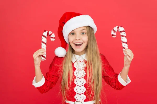 Gestreiftes Zuckerrohr traditionell für den Winterurlaub. Weihnachtsdekor. Ideen zur Weihnachtsdekoration. Das Weihnachtsmann-Kostüm hält Weihnachtsbonbons in der Hand. Erstellen Sie einzigartige Dekorationen. Süße Kindheit — Stockfoto