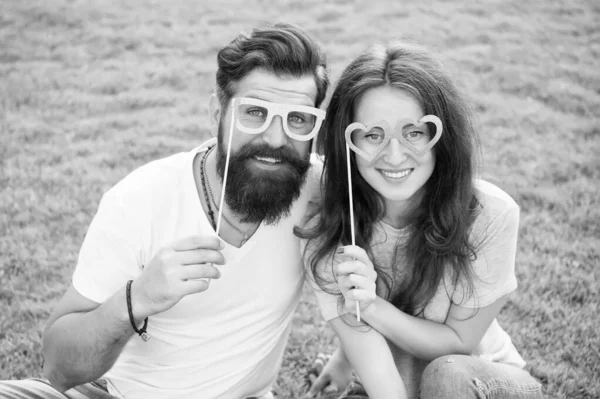 Man bearded hipster and pretty woman in love. Summer vacation. Happy together. Couple in love cheerful youth booth props. Emotional couple radiating happiness. Love story. Couple relaxing green lawn