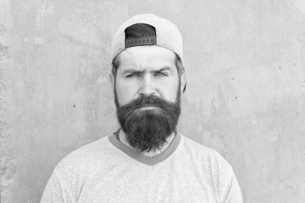 Bearded and moustached. Bearded man on grey wall. Serious bearded hipster in casual summer style. Caucasian guy wearing long mustache and beard hair on bearded face